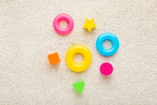istock Different colorful plastic playing shapes on white soft home carpet background. Closeup. Baby development toys. Top down view. 2210380654