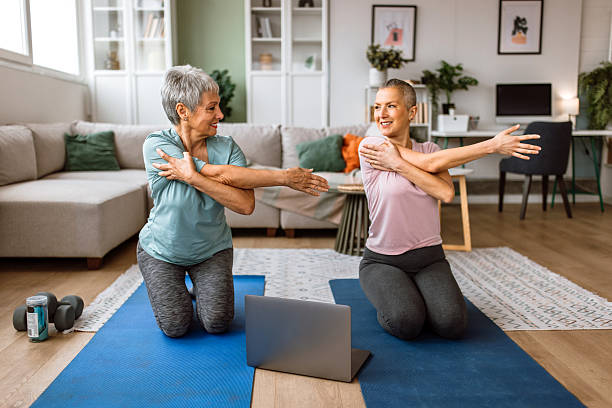 istock Mother and daughter exercising at home together, while watching online video class 2210380764