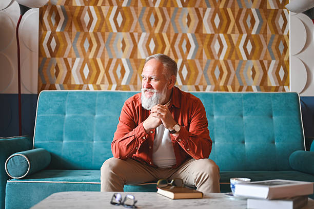 Senior man sitting on sofa and looking away while thinking about something