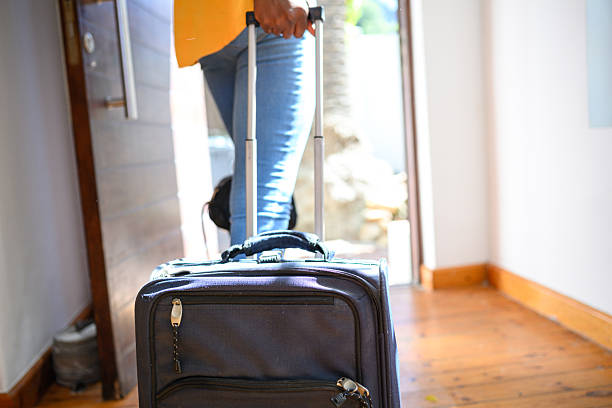istock Close up black woman pulling wheeled luggage at front door 2210381635
