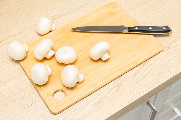 champignon mushrooms lie on a wooden cutting board. cooking mushrooms. High quality photo