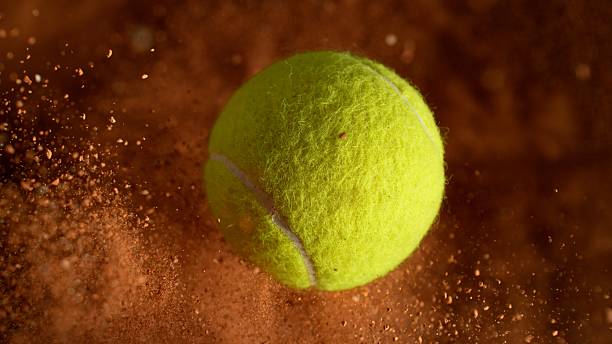 istock Rotating Tennis Ball with Clay Explosion. 2210386560