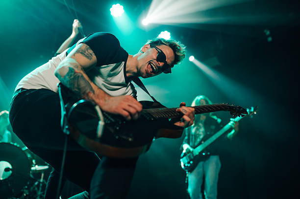 istock Guitarist performing enthusiastically on stage under blue lights 2210390401