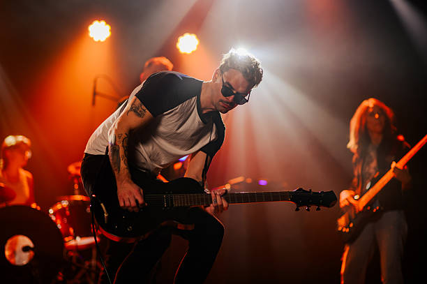 istock Guitarist performing live on stage with band 2210390409