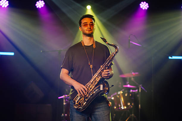 istock Saxophonist performing live on stage with colorful lights 2210390446