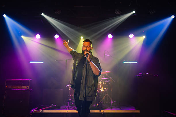 istock Singer performing on stage with microphone and stage lights 2210390454