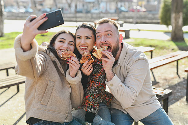 istock Three Joyful Friends Taking Selfie While Eating Pizza Outdoors 2210392179