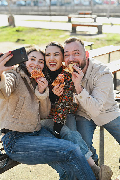 istock Joyful Trio Snapping Playful Selfie While Holding Up Pizza Slices and Smiling 2210392608