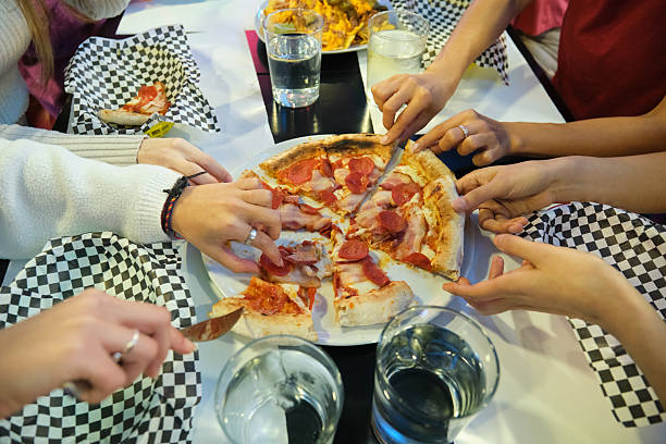 Group of friends enjoying a pepperoni and bacon pizza together at a restaurant