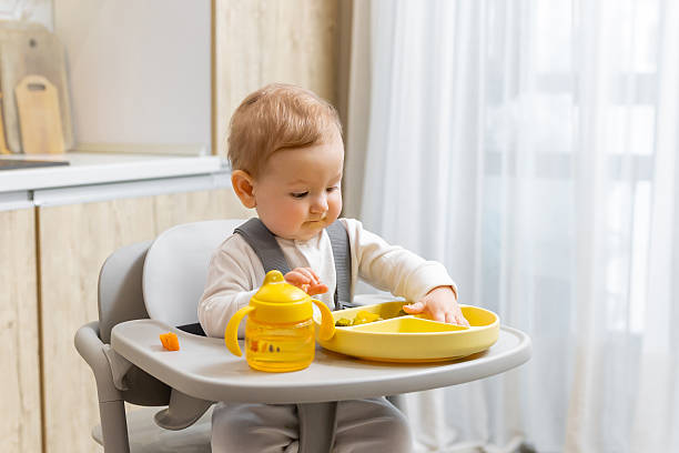 istock Sweet caucasian baby boy making breakfast while sitting on his chair 2210393349