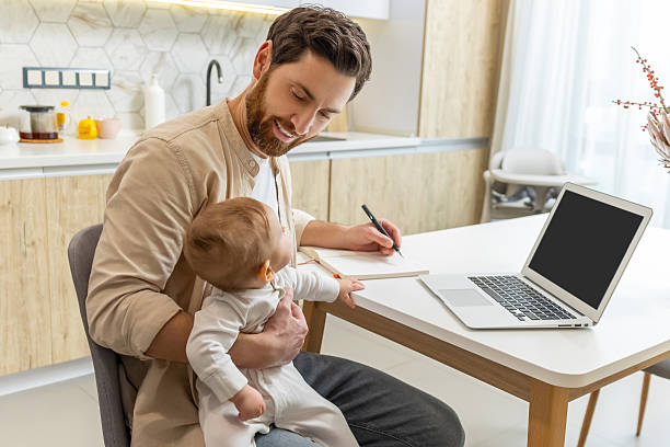 istock Self-employed young man working from home office while talking care of a baby 2210393387