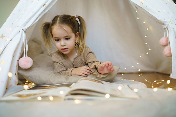 Child whit book lying in tent