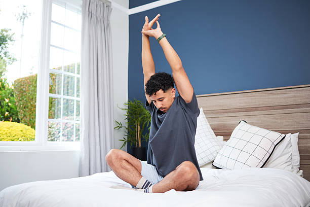 istock Young Man Stretching Morning Relaxation Routine on Bed in Cozy Bedroom 2210396782