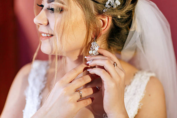 istock A woman is getting ready for a wedding and is putting on her earrings 2210396919