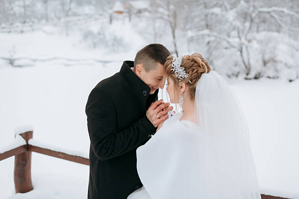 istock A bride and groom are standing on a snowy bridge 2210396960