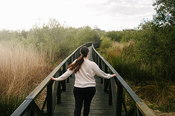 A young woman on a wooden footbridge in a natural area