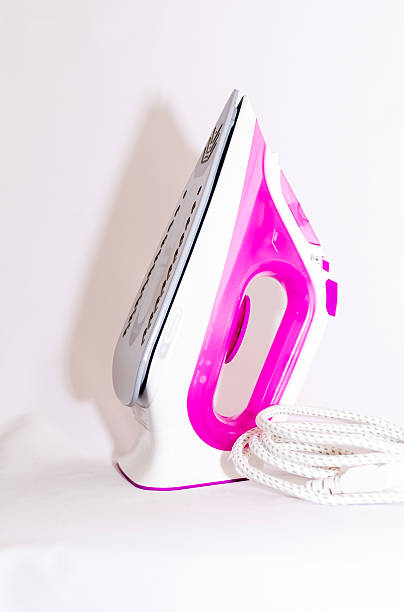 istock Electric iron pink with steam, on white background 2210401596