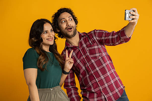 istock Couple taking selfie over mobile phone on yellow background 2210404227
