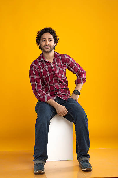 istock Man sitting on block over yellow background 2210404354