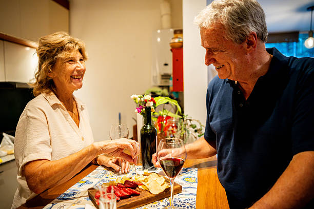 istock Senior couple eating snacks and drinking wine at home 2210407074