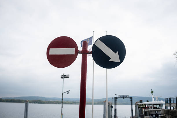 Signs indicate restricted access and navigation directions at a tranquil lakeside dock on a cloudy day. The peaceful setting adds to the ambiance.