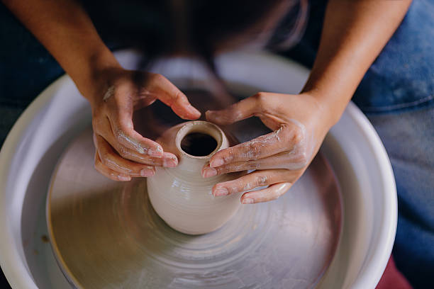 Latina artist shaping ceramic piece with her hands Toma cerrada de las manos de una mujer latina moldeando una pieza de cerámica en su taller. Refleja esfuerzo, enfoque y detalle artesanal. homemade pottery wheel stock pictures, royalty-free photos & images