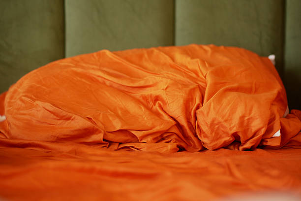 A cozy orange bedding set draped against a soft green backdrop that complements it
