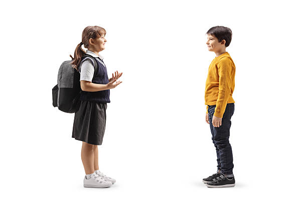 istock Girl in a school uniform carrying a backpack and talking to a boy 2210410773