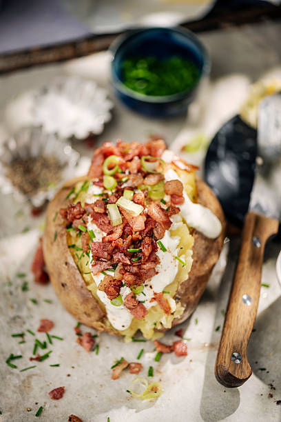 Baked potato just out of the oven filled with a sour cream mix of scallions and chives and topped off with some crispy bacon bits. Recipe: Rub your potato with olive oil and salt; this will give the skin a nice texture when baked. Prick the surface of the potato with a fork in a couple of places and put it on a rack above a baking tray in a hot oven at around 180C for an hour or so, depending on the size.Take it out of the oven, cut it open, and add some butter and a topping of your choice. Enjoy!