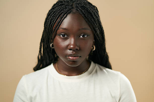 Young black woman with braids posing in studio with neutral background