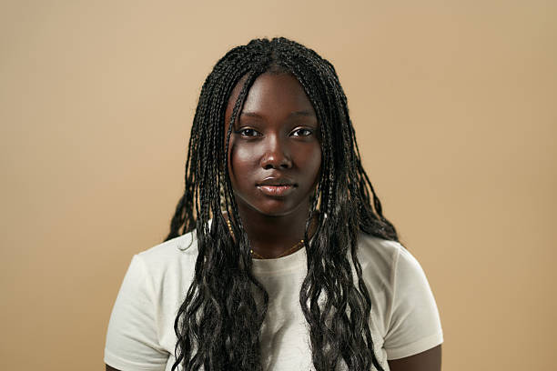 istock Young black woman with braids posing against beige background 2210411618