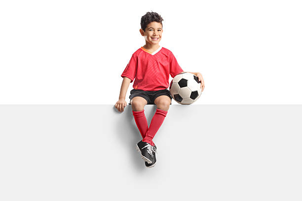 istock Asian kid in a football jersey sitting on a blank panel 2210412745