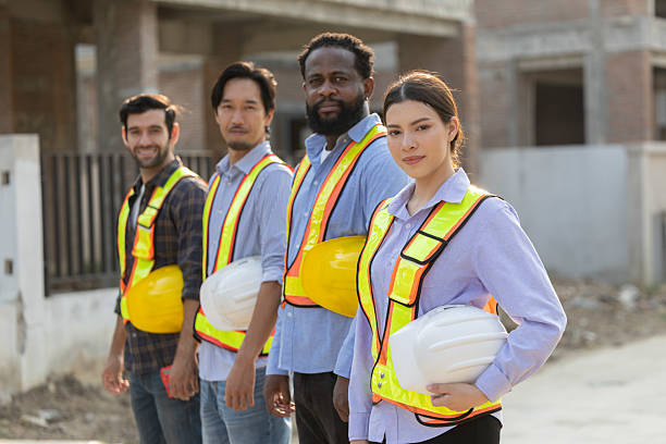 istock Team of construction workers in safety gear pose together at a building site 2210416432