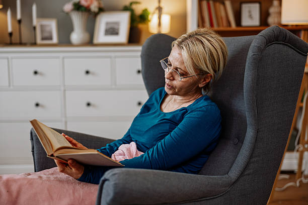 istock Senior Woman Reading a Book and Smiling While Using a Phone 2210419848