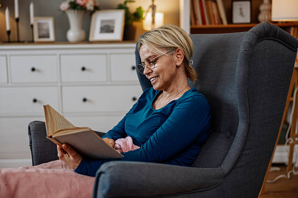 istock Senior Woman Reading a Book and Smiling While Using a Phone 2210419855