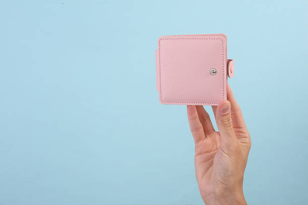 istock Female hand holding pink leather wallet on blue background 2210420840