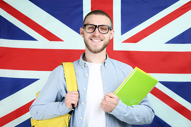 istock Young man with backpack and notepads on British flag background 2210422390