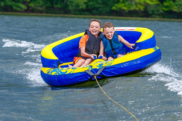 istock Two smiling boys on an inflatable raft on a lake pulled by a boat on a summer day. 2210423554