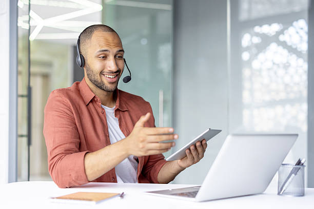 istock Man with headset and laptop inside office at workplace. Support worker consulting and helping customers consumers remotely 2210425914