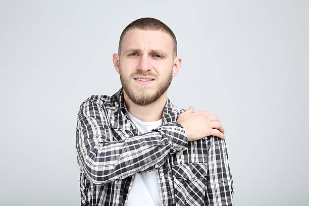 istock Young man having pain in shoulder on grey background 2210428162