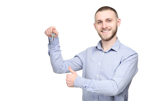 istock Young man holding silver key on white background 2210429257