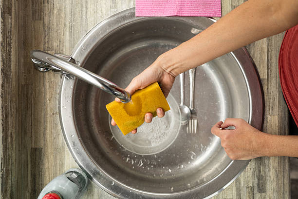 istock Woman’s Arm Wetting Sponge Over Kitchen Sink 2210431782