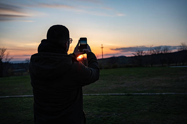 istock Man Taking Photo of Scenic Sunset Outdoors Using Smartphone Camera 2210432121