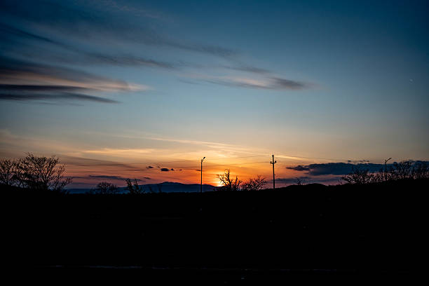Serene sunset scene featuring vibrant colors in the sky, silhouetted trees, and a tranquil ambiance. Captured during twilight, this peaceful image provides a soothing and beautiful portrayal of nature.