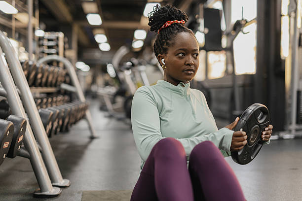 istock Focused woman lifting weights in vibrant gym setting 2210433740