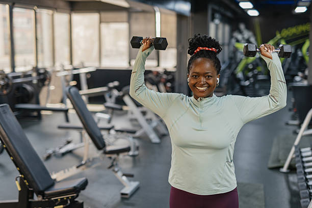 istock Joyful woman lifting weights with confidence in gym 2210433829