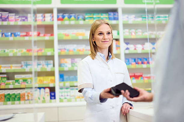 istock Smiling Female Pharmacist Assisting Customer At a Modern Pharmacy Counter 2210436391