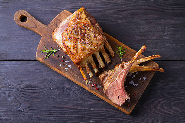 istock Roasted rack of lamb. Lamb chops with vegetables on serving wooden board 2210437076
