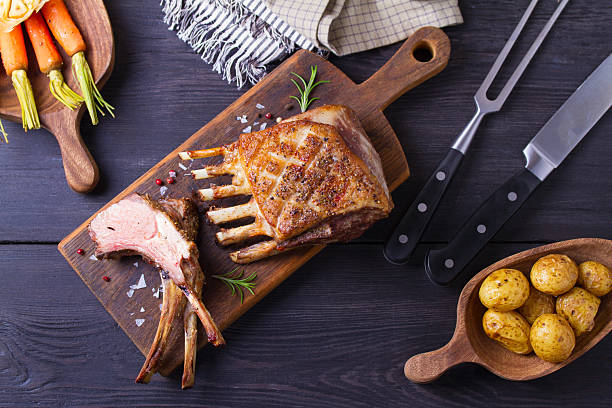istock Roasted rack of lamb. Lamb chops with vegetables on serving wooden board 2210437126