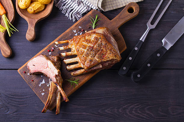 Roasted rack of lamb. Lamb chops with vegetables on serving wooden board